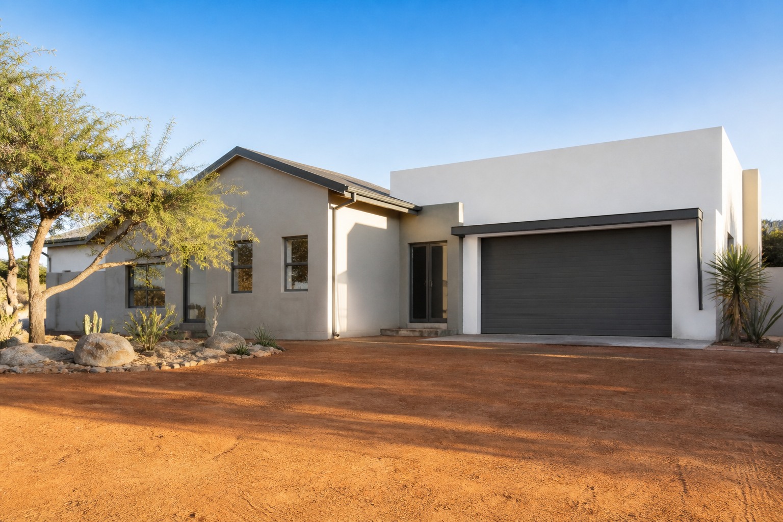 Completed house exterior on a cleared plot with a wide red-earth driveway