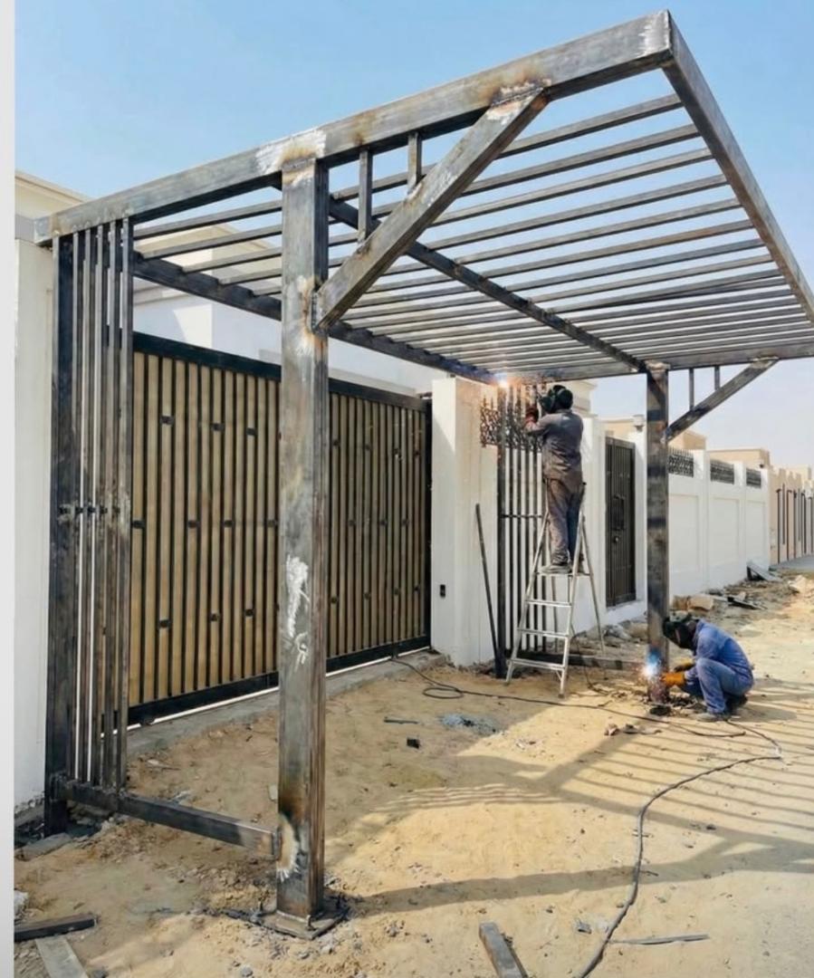 Workers fabricating a steel canopy frame outside a residence